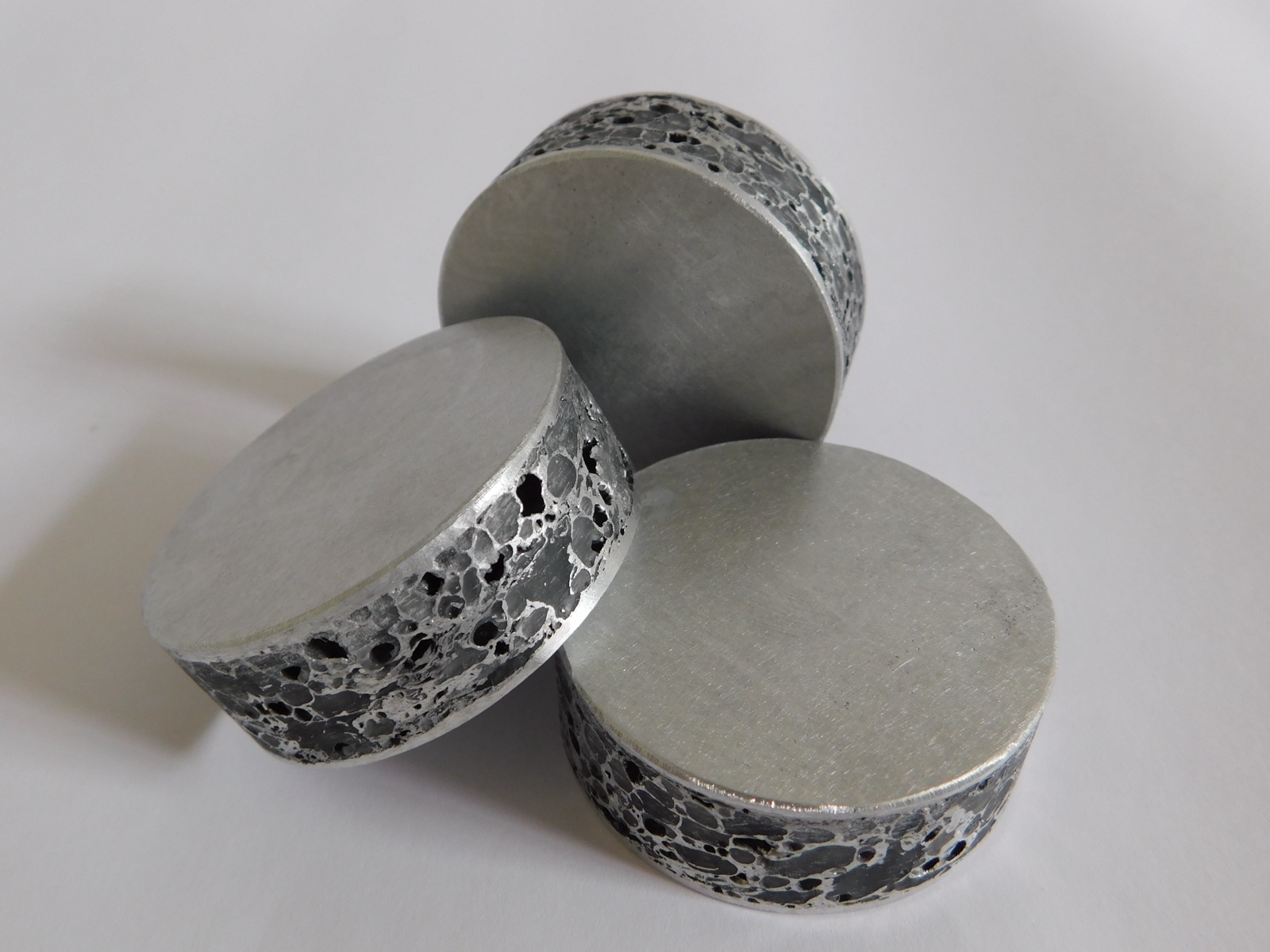 Three round aluminum foam discs stacked on top of one another; the top faces are milled smooth, while the cell structure lies exposed on the circumferential faces.
