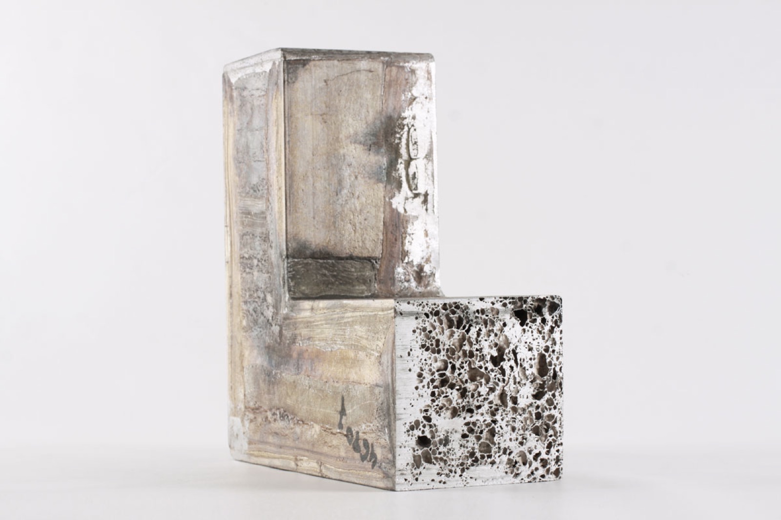 An angled component of aluminum foam with a cast skin; the cut end face shows the closed cell structure of the core.