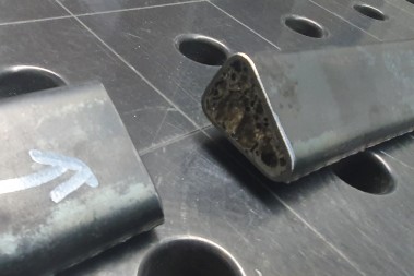 Close-up of two profile ends on a perforated table; the aluminium foam in the cavity is visible in the cut profile.