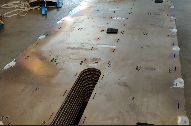 Large flat base plate on the hall floor, with numerous holes and a bundle of thin tubes at the end face.