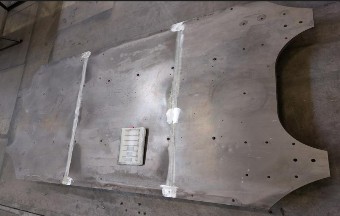 Large base plate with two continuous longitudinal seams and a cut-out at the end face; a job card lies on the plate.