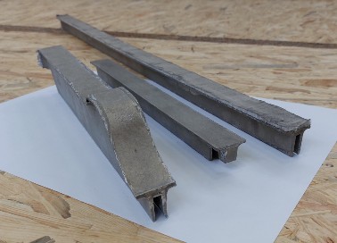 Three aluminium foam profiles of different lengths, foamed in the mould, side by side on a light sheet.