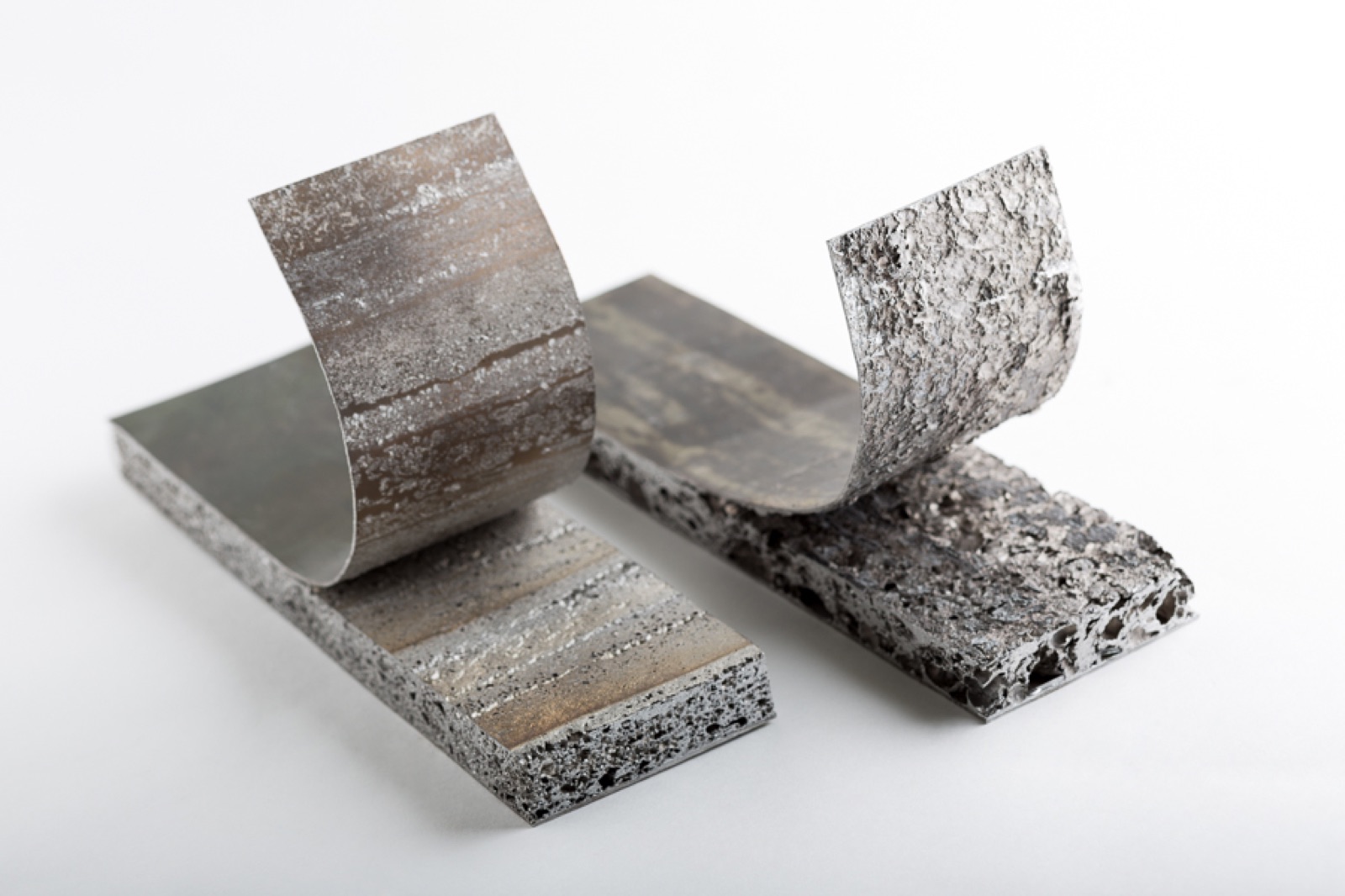 Two sandwich specimens with the cover layer bent back. Aluminum foam is still attached to the undersides of the bent-back cover layers.
