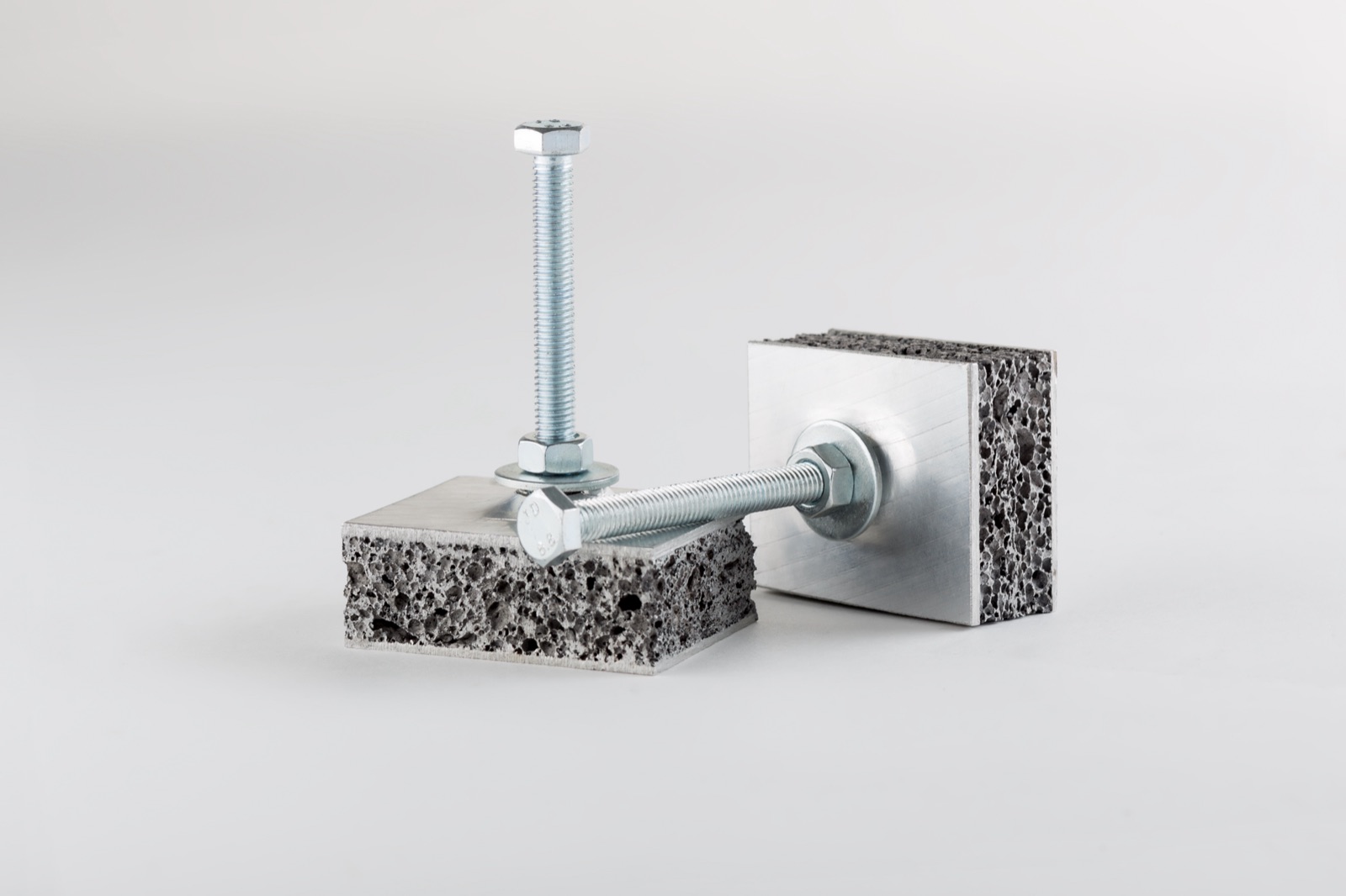 Two sandwich blocks with the foam core cut open; a bolt is set into each, one vertical and one horizontal, each with a washer and nut.